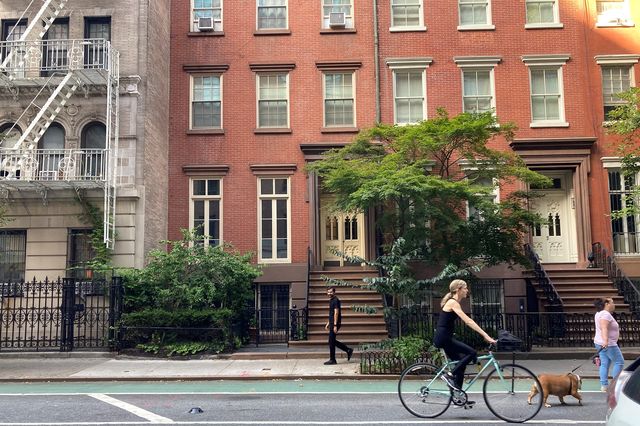 a cyclist rides in front of a townhouse